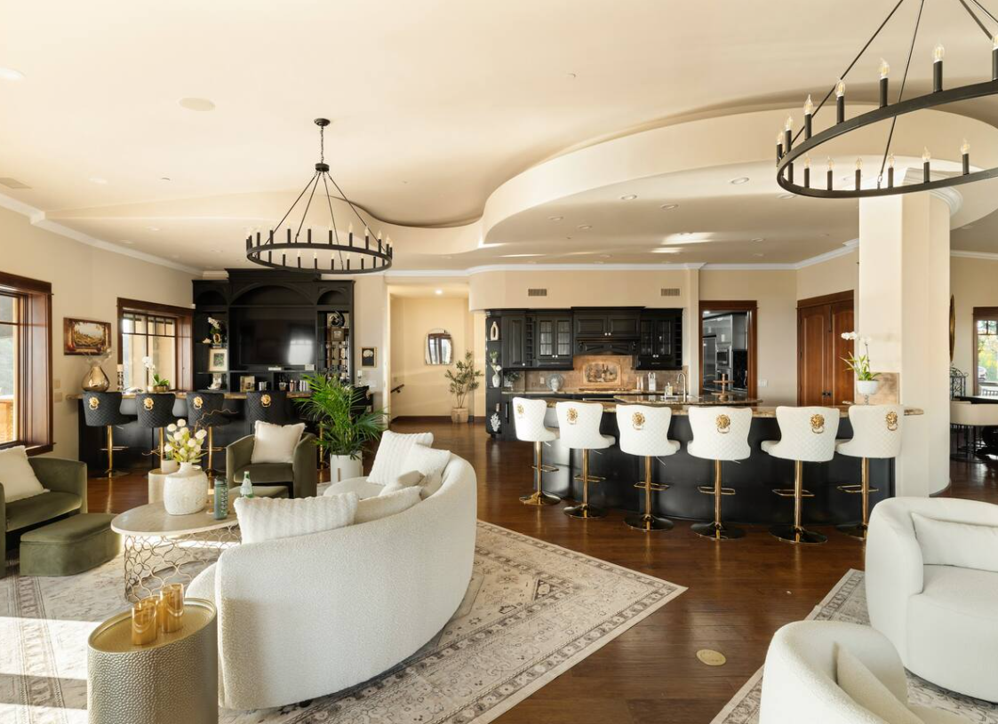 Great room with curved boucle sofa, chandelier, and private bar