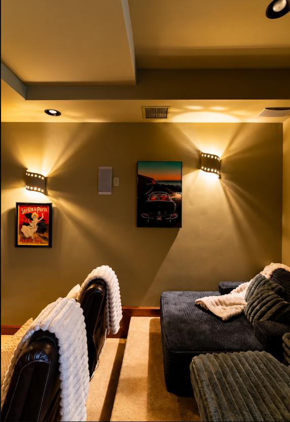 Warm sconce lighting, vintage posters, and recliners in the theater