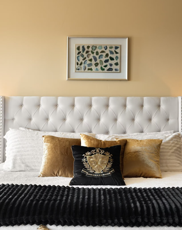 Tufted headboard with gold velvet pillows and framed art