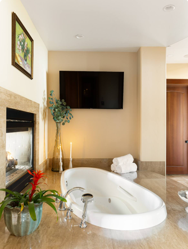 Soaking tub beside a travertine fireplace
